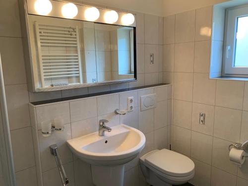 ein Badezimmer mit einem Waschbecken, einem WC und einem Spiegel in der Unterkunft Ferienwohnung "Waldallee 15" in Sankt Peter-Ording