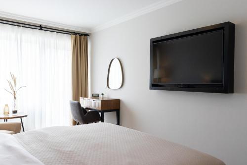 a hotel room with a television on the wall at Moderne Ferienwohnung mit Sonnenterrasse & Gartenblick - Strandnah und Parkplatz in ruhiger Lage - hoher Schlafkomfort in Scharbeutz