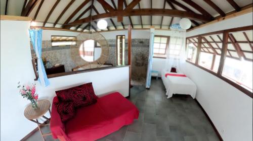 sala de estar con sofá rojo y espejo en Fare Oviri Lodge, en Opoa