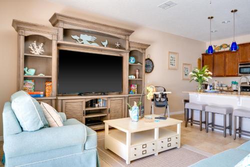 ein Wohnzimmer mit einem großen TV und einer Küche in der Unterkunft Luxury Family Villa 4 BR & Pool & BBQ at Solterra Resort in Davenport