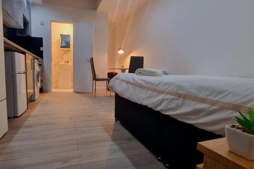 a bedroom with a bed and a kitchen and a table at Brand new collection of studios close to Tube Station in London