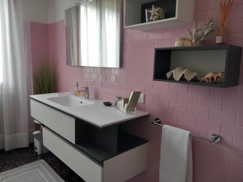 een roze badkamer met een wastafel en een spiegel bij Casa Lola in Cavallino-Treporti