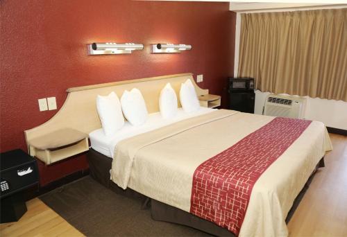 a hotel room with a large bed with white pillows at Red Roof Inn Enfield in Enfield