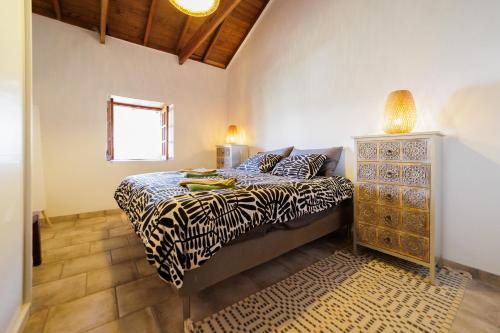 een slaapkamer met een bed met zebraprint en een dressoir bij Finca Los Arcos del Laurel in Moya