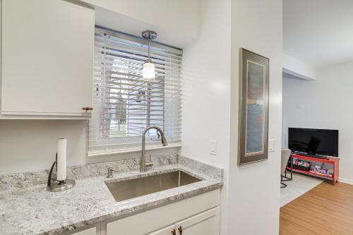 a white kitchen with a sink and a tv at South Haven Condo - Walk to Lake Michigan! in South Haven