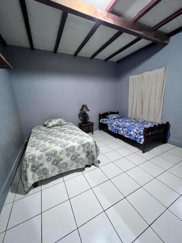 a bedroom with two beds and a tiled floor at Hotel Pacific Surf with AC Best Room In Tunco Beach in Tamanique