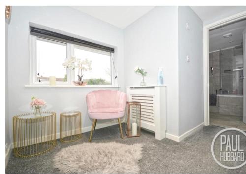 a living room with a pink chair and a window at Modern three bed house in Ditchingham