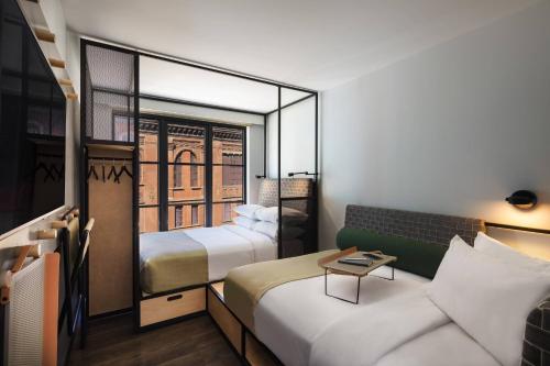 a hotel room with two beds and a couch at Moxy NYC East Village in New York