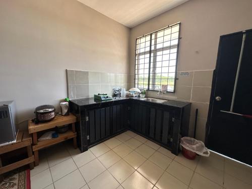 a kitchen with a black counter and a window at D’ QR Homestay Kuantan in Kuantan