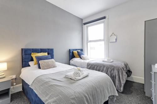 Duas camas num quarto com uma janela em Beautiful Spacious four bedroom house with parking for 2 cars, 5 minute walk to southend station em Southend-on-Sea