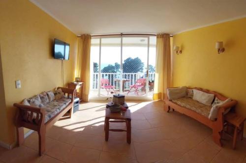 uma sala de estar com 2 sofás e uma varanda em Depto en la playa 3 dormitorios em Horcón