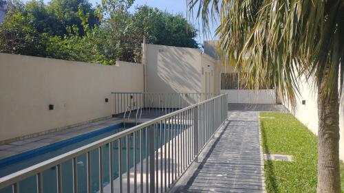 een zwembad met een hek en een palmboom bij El Bicentenerio in San Miguel de Tucumán