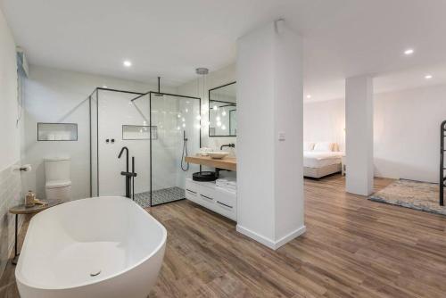 1 cama y baño con bañera blanca y ducha. en 10 Wharf Street - a tropical family home, en Port Douglas