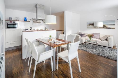 Il dispose d'une cuisine et d'un salon avec une table en bois et des chaises blanches. dans l'établissement NeysTime, à Norderney