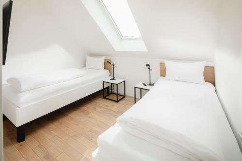 two white beds in a room with a skylight at Quartier M12 in Norderney