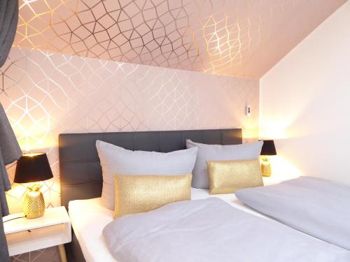 a bedroom with two beds with white and gold pillows at Glamory Winterberg Ferienwohnung Pool Sauna Wifi 6 Personen near Lift Balkon PS4 in Winterberg