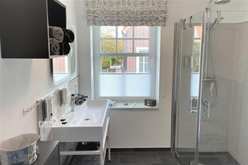 uma casa de banho branca com um lavatório e um chuveiro em Ferienwohnung Inselherz em Wangerooge