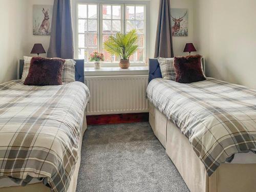 a bedroom with two beds and a window at Roosters Retreat in Minehead
