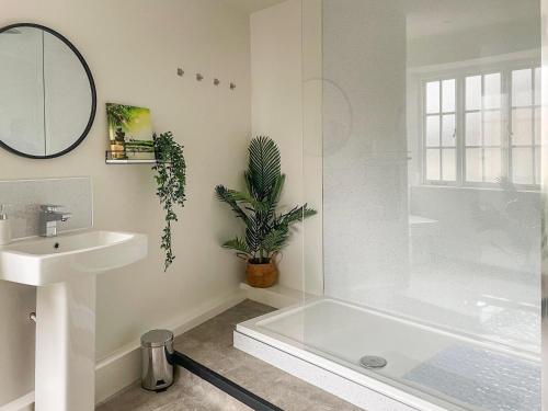 a white bathroom with a sink and a tub and a mirror at Roosters Retreat in Minehead