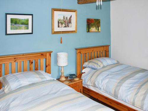 2 Betten in einem Schlafzimmer mit blauen Wänden in der Unterkunft Spoutscroft Cottage in Austwick
