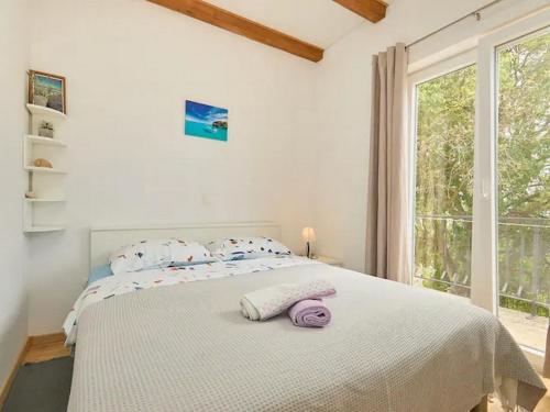 a white bedroom with a large bed with a window at Apartments with parking spaces Babino Polje, Mljet - 22321 in Babino Polje