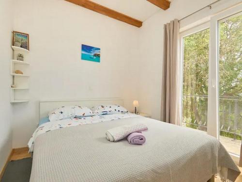 a white bedroom with a large bed with a window at Apartments with a parking space Babino Polje, Mljet - 22321 in Babino Polje