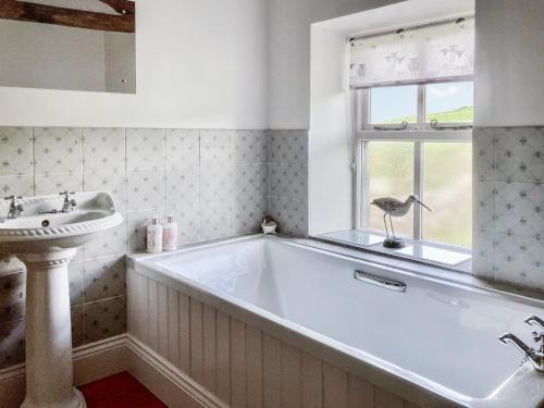 eine große Badewanne im Bad mit Waschbecken in der Unterkunft Spoutscroft Cottage in Austwick