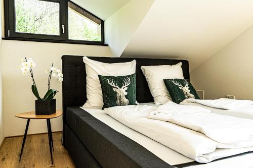- un lit avec des draps blancs et des oreillers verts dans l'établissement Alpenloft Ausblick, à Oberstaufen