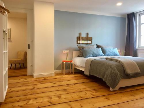 a bedroom with a bed with blue walls and wooden floors at Rosinas - Fräulein Thäsler in Oberstaufen