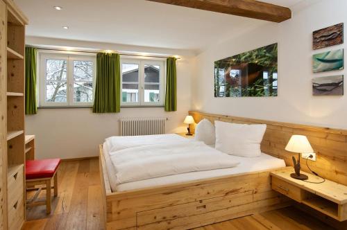 a bedroom with a bed and a desk and two windows at Hochgrat in Oberstaufen