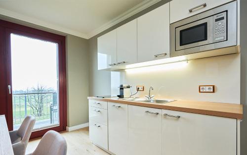 eine Küche mit weißen Schränken und einer Mikrowelle in der Unterkunft Apartement Jasmund mit Ostseeblick - Haus Fore zu Schloss Ranzow in Lohme