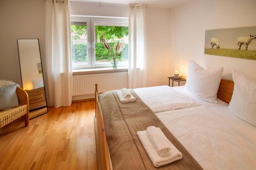 - une chambre avec un grand lit blanc et des serviettes dans l'établissement Up Warft - West, à Krummhörn