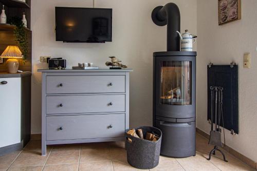 a living room with a wood stove and a dresser at Lüttje Scholle in Krummhörn