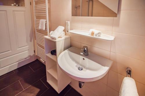 W łazience znajduje się biała umywalka i lustro. w obiekcie Int Hörn 7 OG w mieście Krummhörn