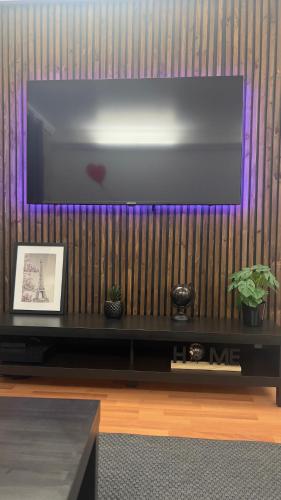 un salon avec une télévision murale à grand écran dans l'établissement Le joyau caché - Paris 2024, à Arnouville-lès-Gonesse