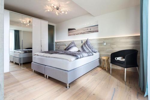 1 dormitorio con 1 cama y 1 silla en Schippers Huus 04 - Bismarckloft, en Norderney