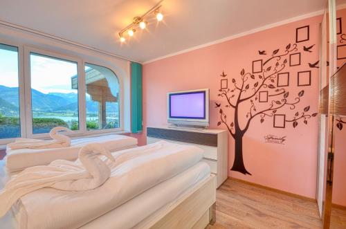 two beds in a room with a tv and a tree at Eichenhof Top 2 - by Alpen Apartments in Zell am See