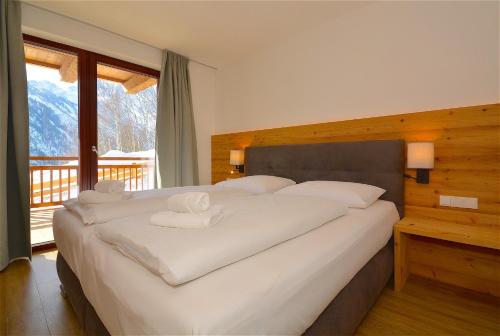カプルーンにあるSki-in Ski-out Chalet Maiskogel "Bergli" - by Alpen Apartmentsのベッドルーム(白い枕の大型ベッド1台付)