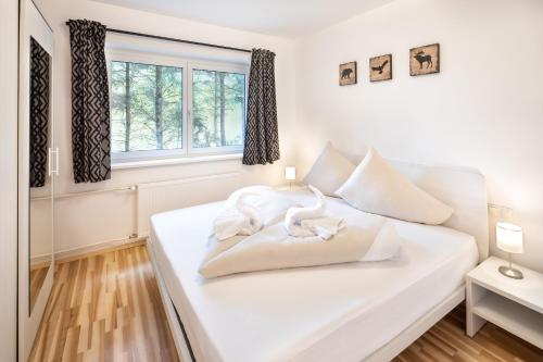 a white bed with two white swans on it at Mozart Top 1 - by Alpen Apartments in Zell am See
