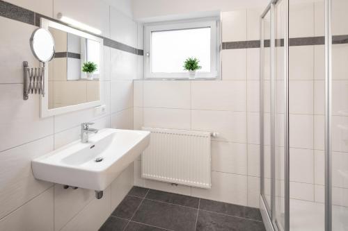 a white bathroom with a sink and a mirror at Mozart Top 1 - by Alpen Apartments in Zell am See