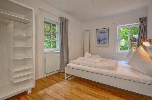 a white bedroom with a bed and two windows at Villa Alpenbach - by Alpen Apartments in Zell am See
