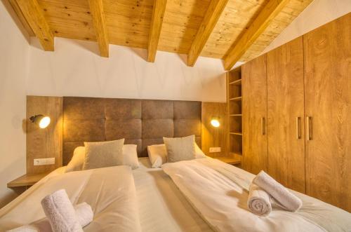 a bedroom with a large white bed with wooden cabinets at Ski-in Ski-out Chalet Maiskogel 17A - by Alpen Apartments in Kaprun