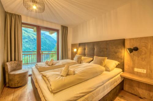 Ski-in Ski-out Chalet Maiskogel 17A - by Alpen Apartments في كابرون: غرفة نوم بسرير كبير مع نافذة كبيرة