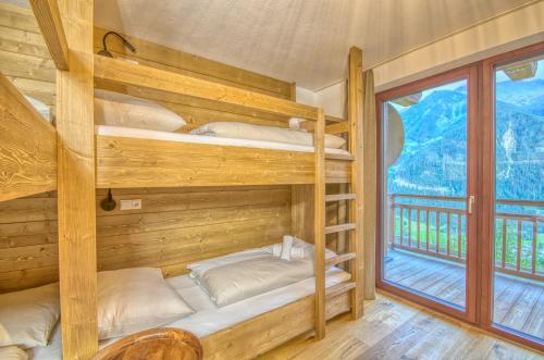 two bunk beds in a wooden room with a window at Ski-in Ski-out Chalet Maiskogel 17A - by Alpen Apartments in Kaprun