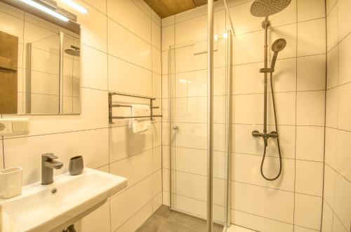 La salle de bains blanche est pourvue d'une douche et d'un lavabo. dans l'établissement Haus Kitzsteinhorn 6 - by Alpen Apartments, à Kaprun