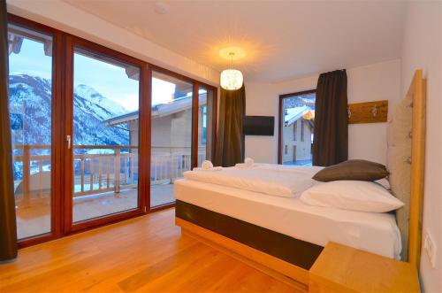 a bedroom with a bed and a large window at Ski-in Ski-out Chalet Maiskogel 13B - by Alpen Apartments in Kaprun