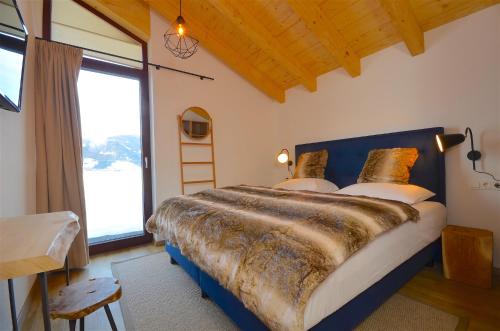 カプルーンにあるSki-in Ski-out Chalet Maiskogel 17C - by Alpen Apartmentsのベッドルーム1室(大きなベッド1台、大きな窓付)