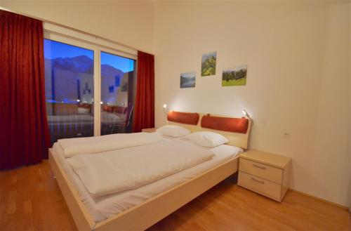 a bedroom with a large bed and a large window at APT Mountain View by - Alpen Apartments in Zell am See