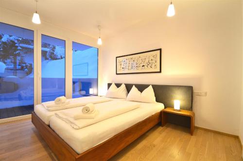 um quarto com uma cama grande e uma janela grande em APT Super Zell -by Alpen Apartments em Zell am See