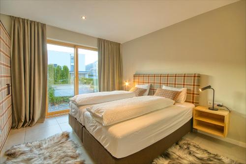 a bedroom with a bed and a large window at Gletscherblick 1 - by Alpen Apartments in Zell am See